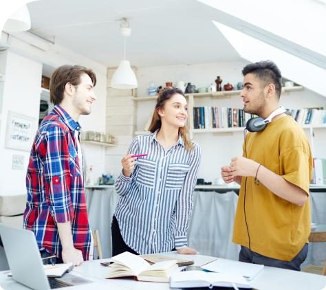 Three students talking in a classroom.